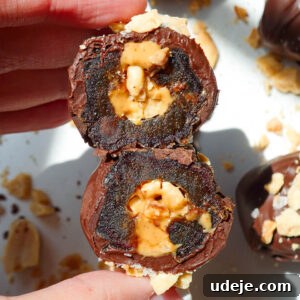 Hand holding a Snickers Stuffed Date with a bite taken out to show the caramel-like texture of the Medjool date and peanut butter filling.