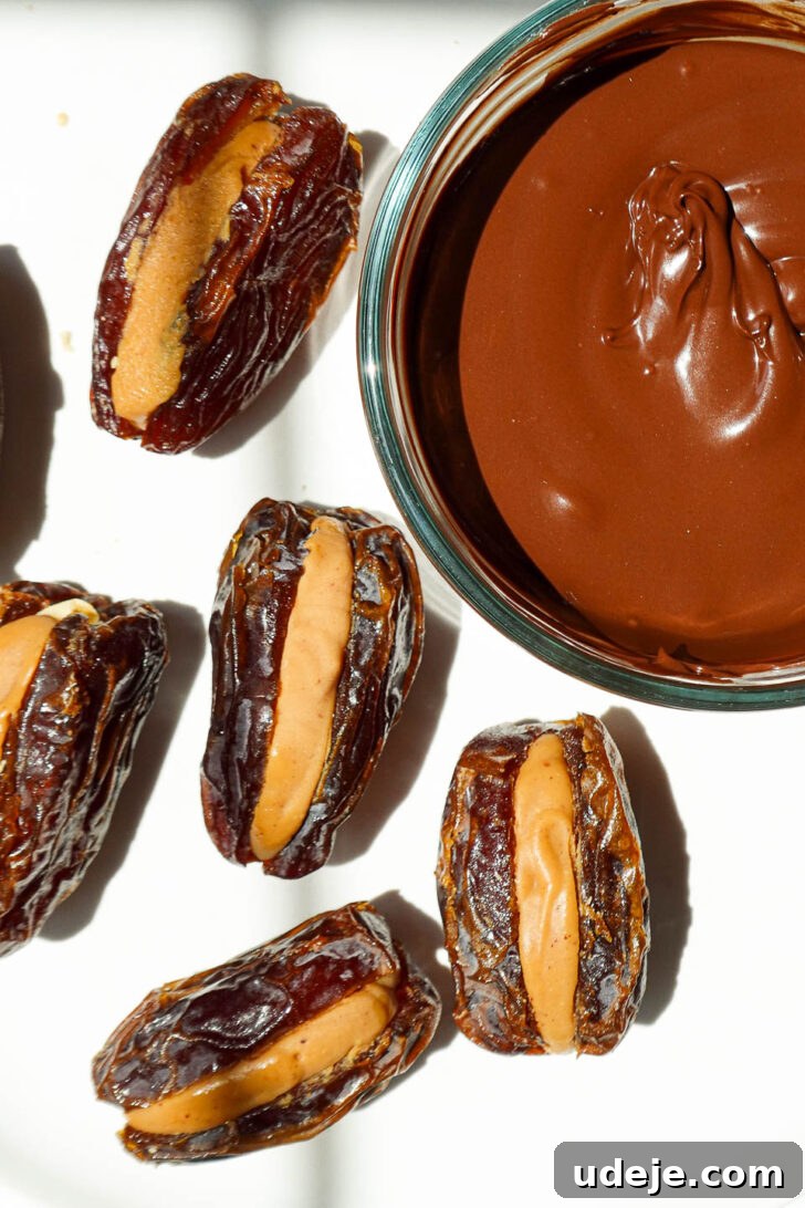 Snickers Date Bombs 6 Process shot of Medjool dates being generously stuffed with creamy peanut butter and crunchy chopped peanuts.