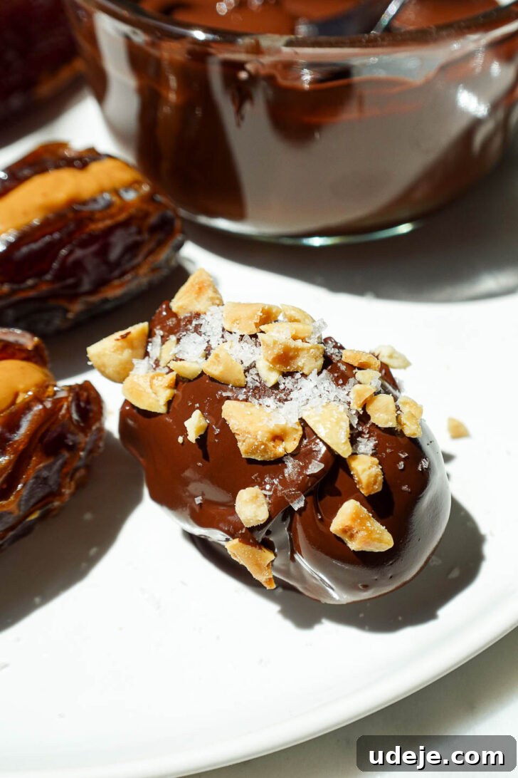 Snickers Date Bombs 7 Snickers Stuffed Dates on a tray, glistening with hardened chocolate coating and flaky sea salt, ready to be enjoyed.
