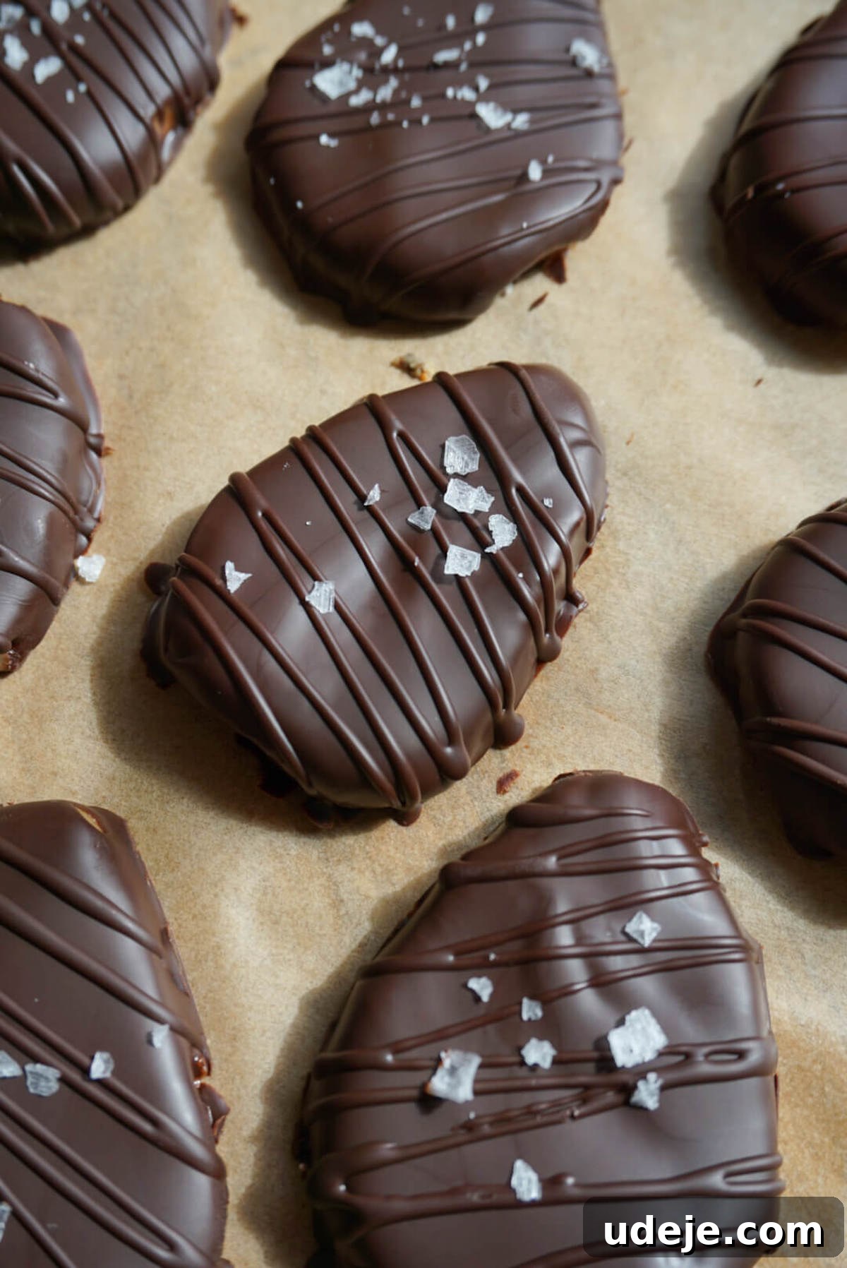 Hand dipping a homemade peanut butter egg into melted vegan chocolate, ready to be sprinkled with sea salt.