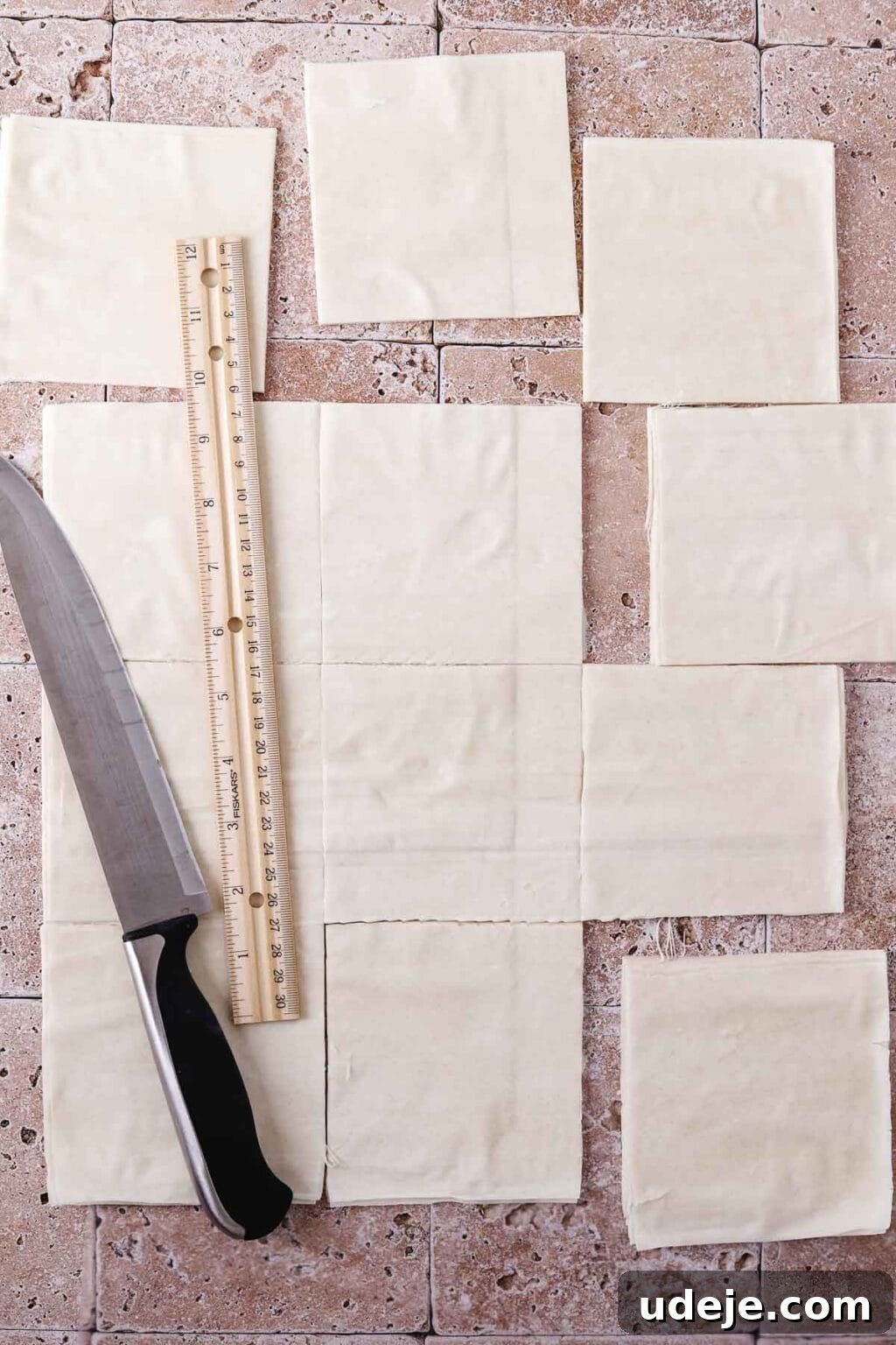 A phyllo sheet on a light stone tiled background, cut into 12 separate squares using a knife and ruler.