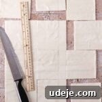 A phyllo sheet on a light stone tiled background, cut into 12 separate squares using a knife and ruler.