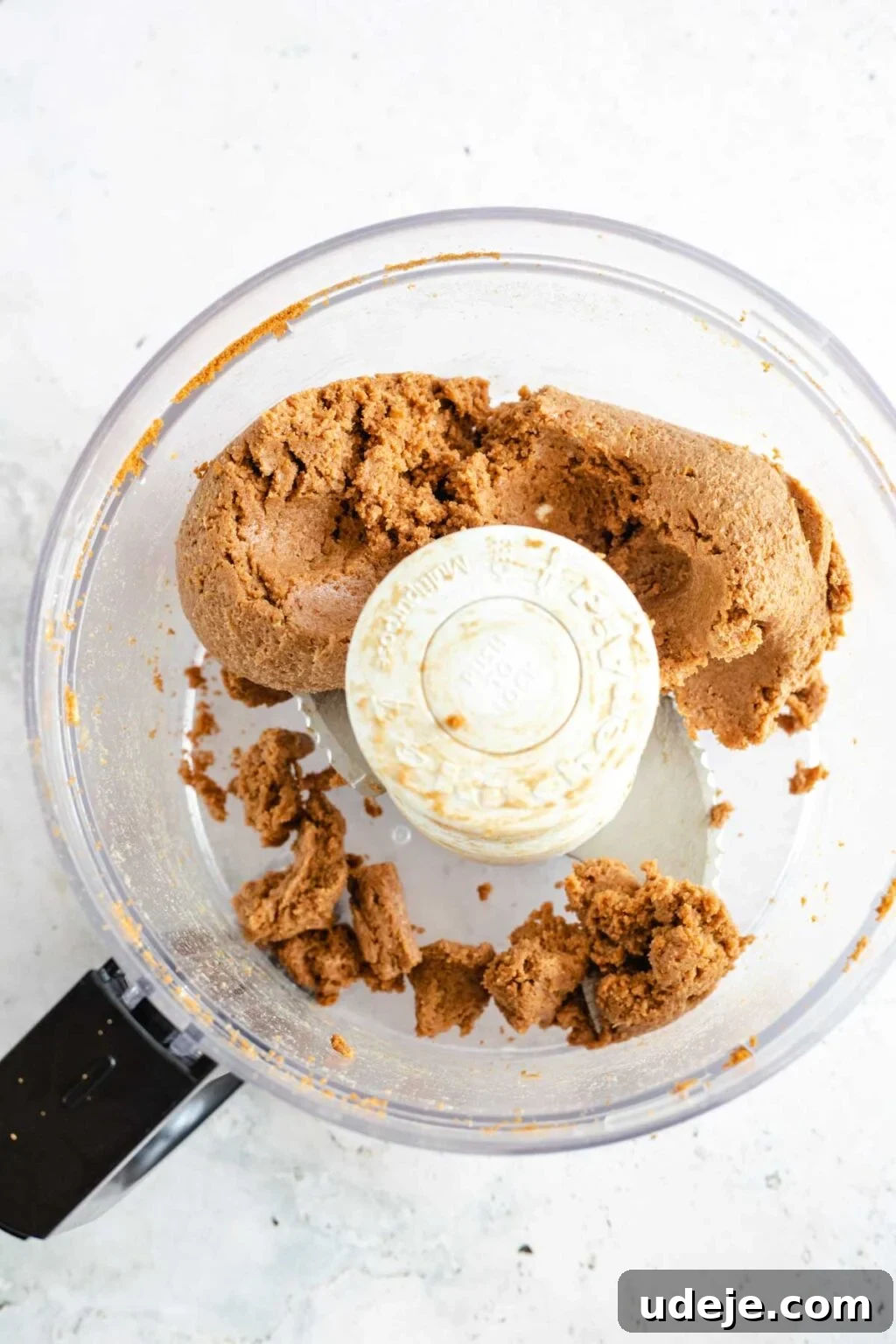 4-Ingredient No-Bake Biscoff Truffles 7 Smooth Biscoff truffle dough expertly formed in a food processor, resting against a light marbled background.