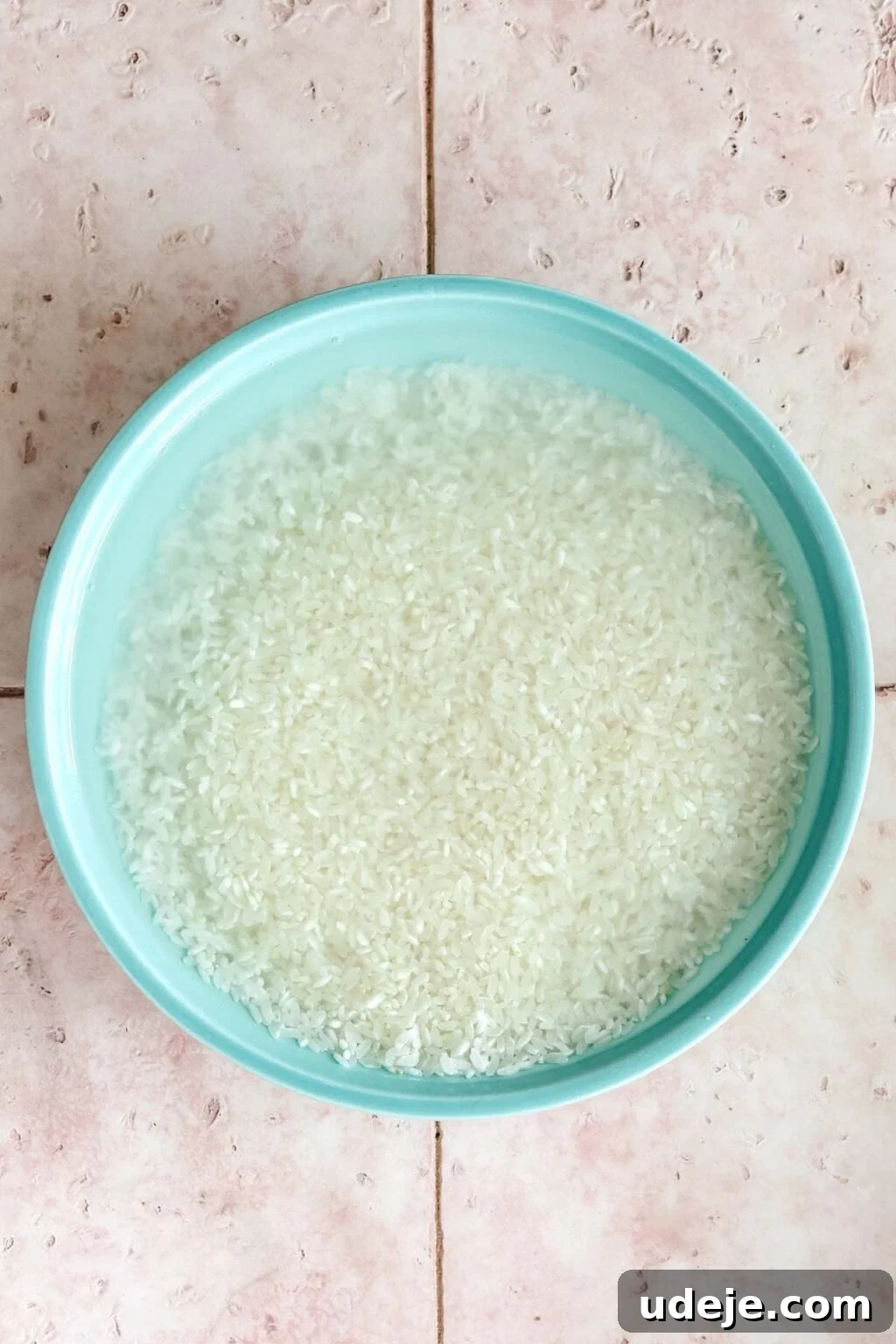 Egyptian Cloud Rice 6 Egyptian rice soaking in water in a blue coloured bowl on a pink tiled background