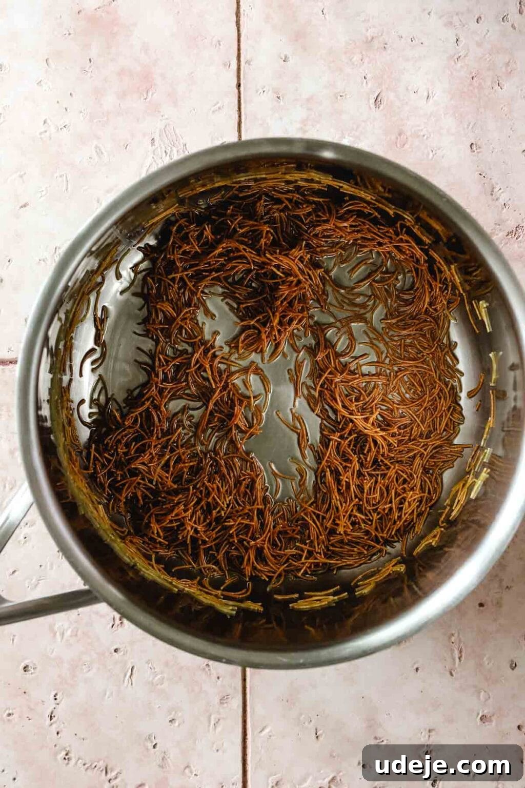 Egyptian Cloud Rice 7 Vermicelli sautéed in metal sauce pan on a pink tiled background