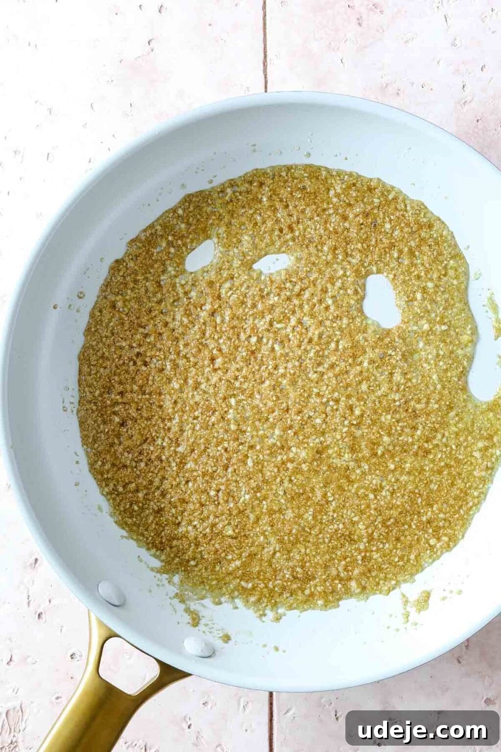 Molokhia: A Timeless Tradition 12 Sautéed garlic and coriander mixture bubbling and turning golden brown in a light-colored skillet, indicating its readiness to be added to the stew.