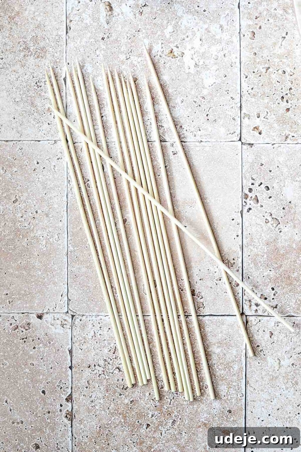 Effortless 15-Minute Air Fryer Chicken Skewers 7 A neat stack of bamboo skewers ready for use, resting on a textured stone tiled background, highlighting their natural and versatile design.