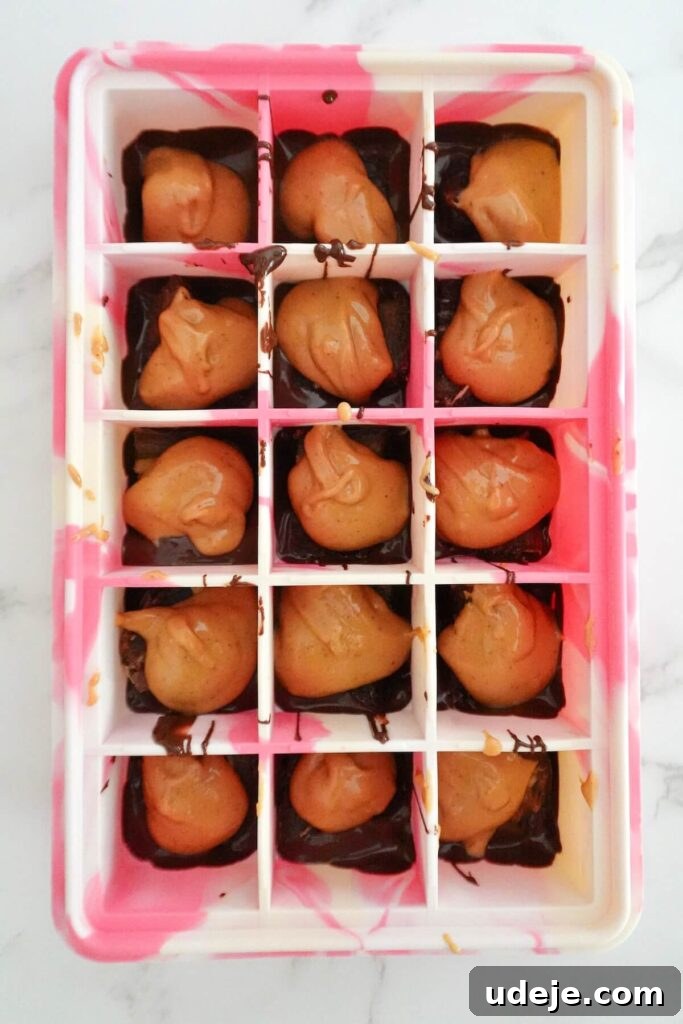 Guilt Free Four Ingredient Snickers Inspired Bites 4 Another step-by-step image showing layers of dates, peanut butter, and crushed peanuts in an ice cube mold.