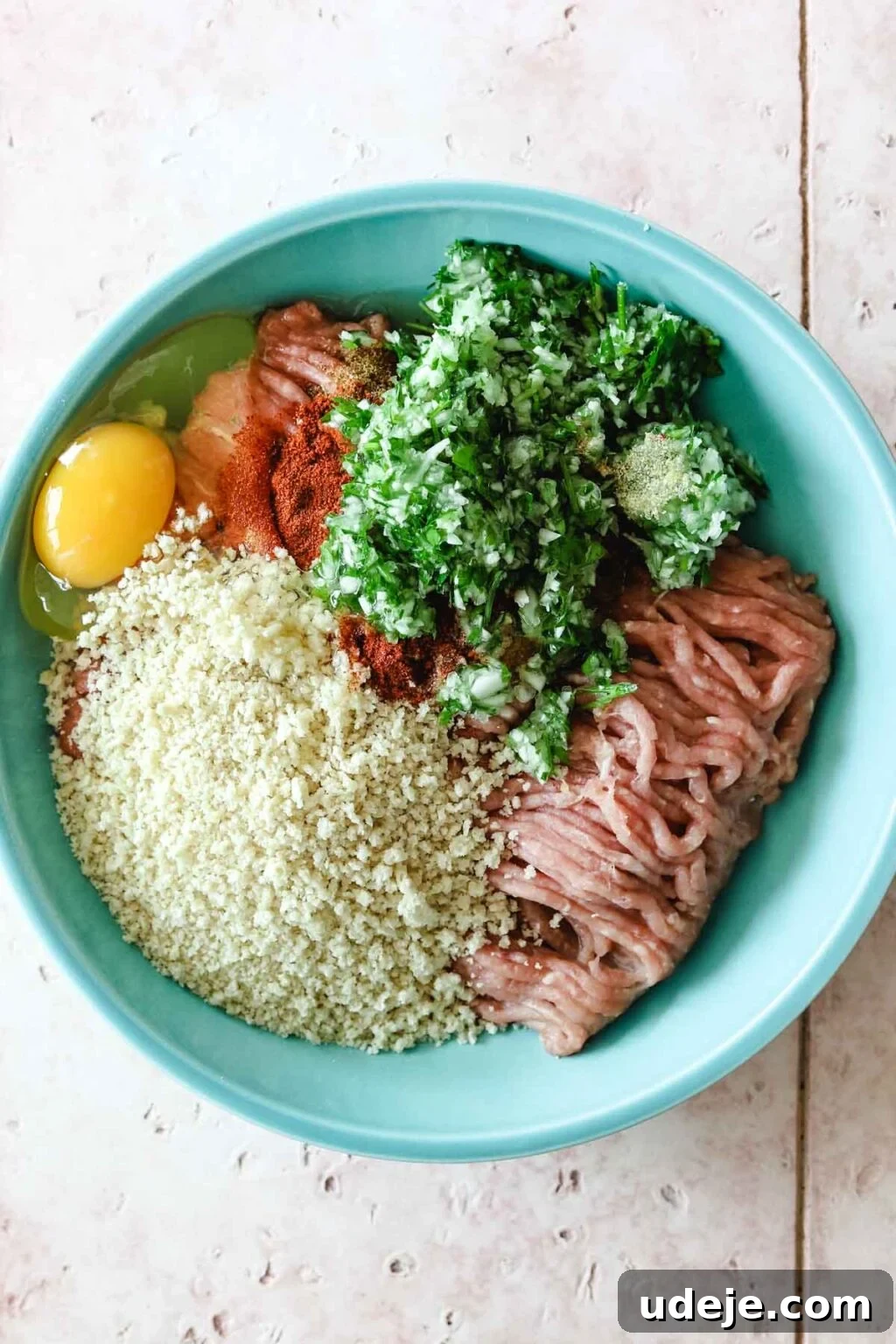 Speedy Chicken Kofta: Grill or Skillet in 20 Minutes 6 Raw chicken kofta ingredients including ground chicken, breadcrumbs, fresh parsley, egg, and a blend of spices, neatly placed in a vibrant blue mixing bowl.