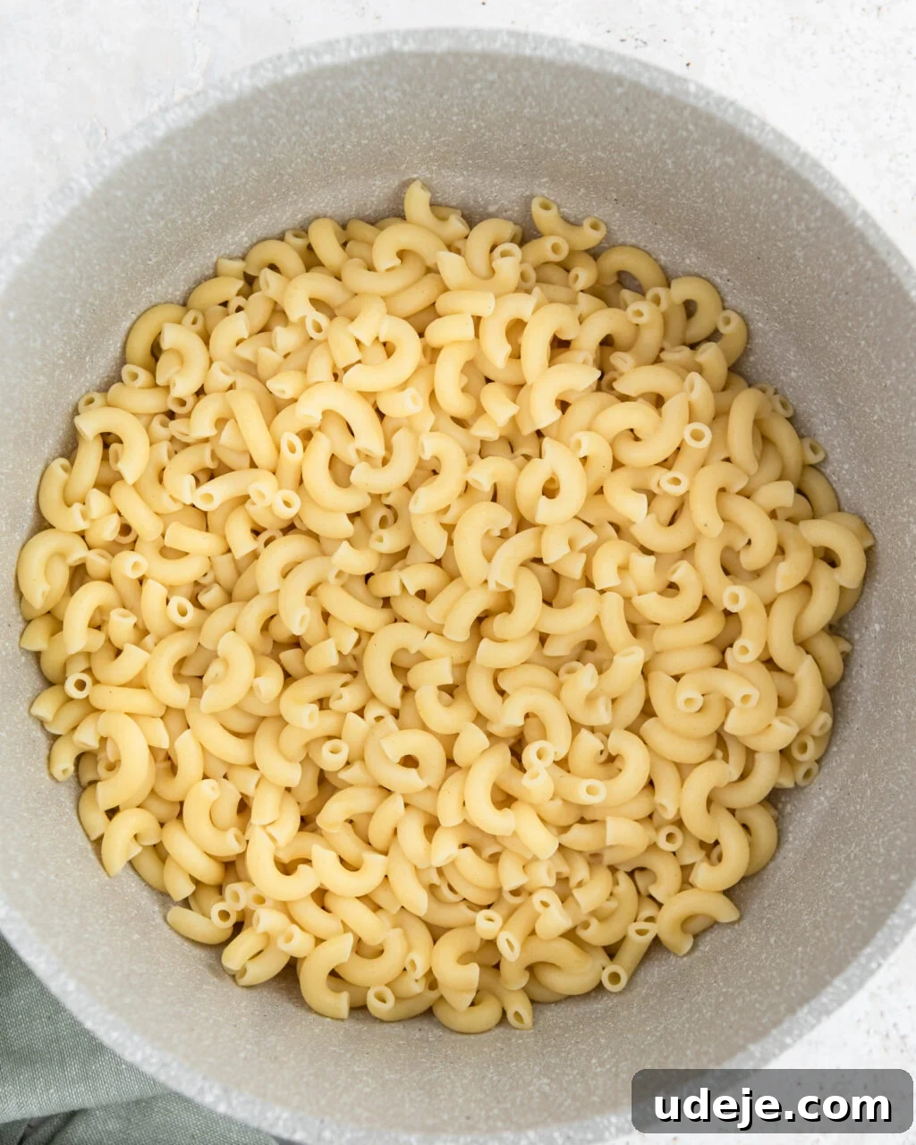 Egypt's Koshari: A Hearty Blend of Rice, Lentils and Pasta 15 cooked macaroni in a light coloured pot with a green towel at the side