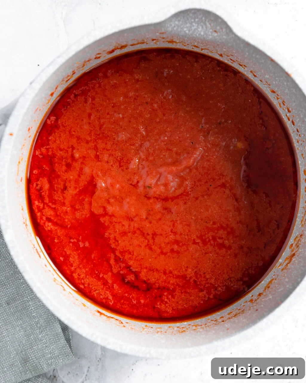 Egypt's Koshari: A Hearty Blend of Rice, Lentils and Pasta 17 light coloured pot with tomato sauce in it and a green towel at the side on a light coloured background