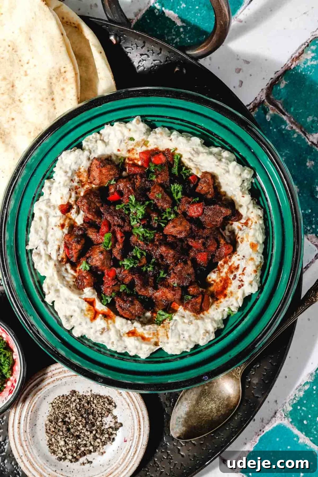 Ali Nazik Smoky Eggplant and Lamb Stew 2 Smoked eggplant and yogurt puree topped with stewed lamb, red peppers, and parsley, served with flatbread on a black tray
