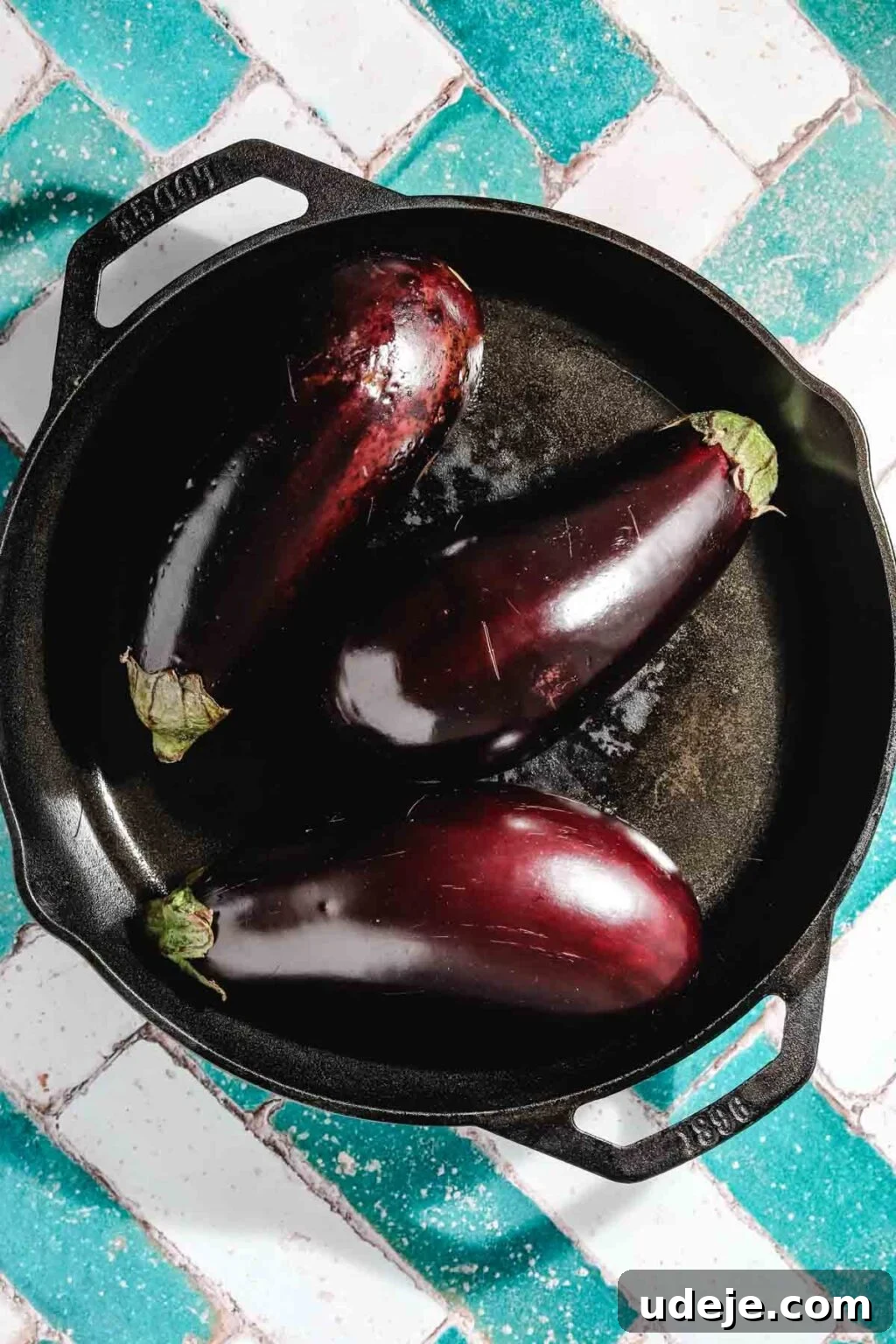 Ali Nazik Smoky Eggplant and Lamb Stew 4 Three whole eggplants in a cast iron pan on a teal and white brick backdrop
