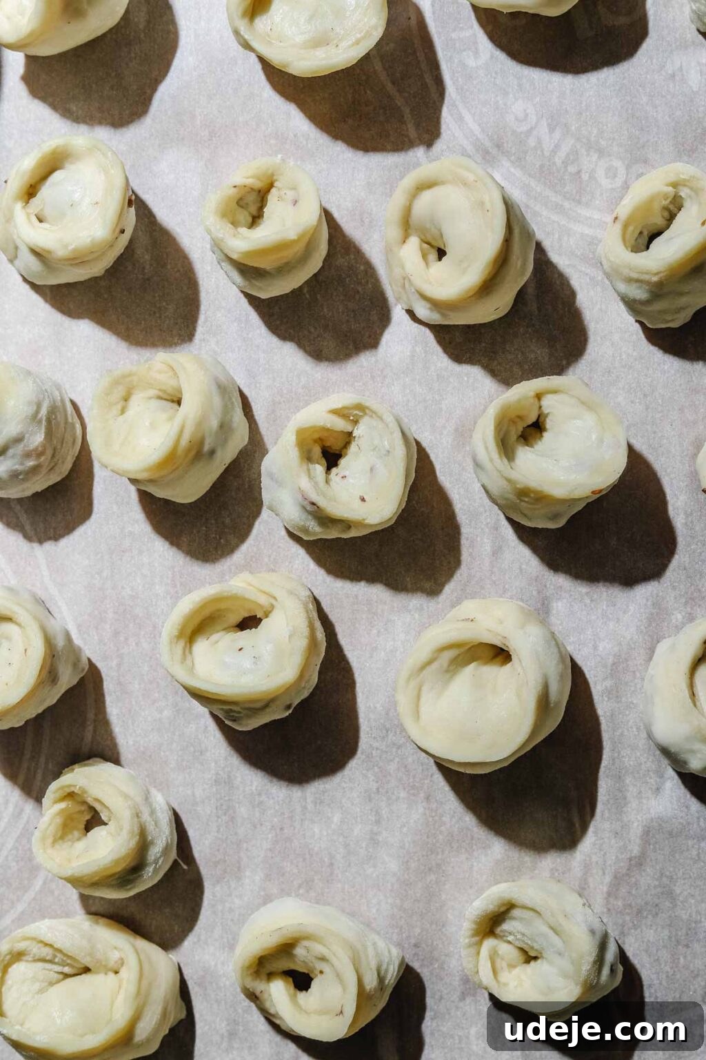 Mastering Homemade Shish Barak: Authentic Yogurt Dumplings 16 Perfectly shaped Shish Barak dumplings neatly arranged on a parchment paper-lined baking sheet, ready for baking.