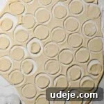 small circles cut out of rolled shish barak dough on a floured surface with a glass cup upide down