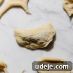 small half circle of dough filled with shish barak filling with scraps of dough and circles of dough around it on a light marble background