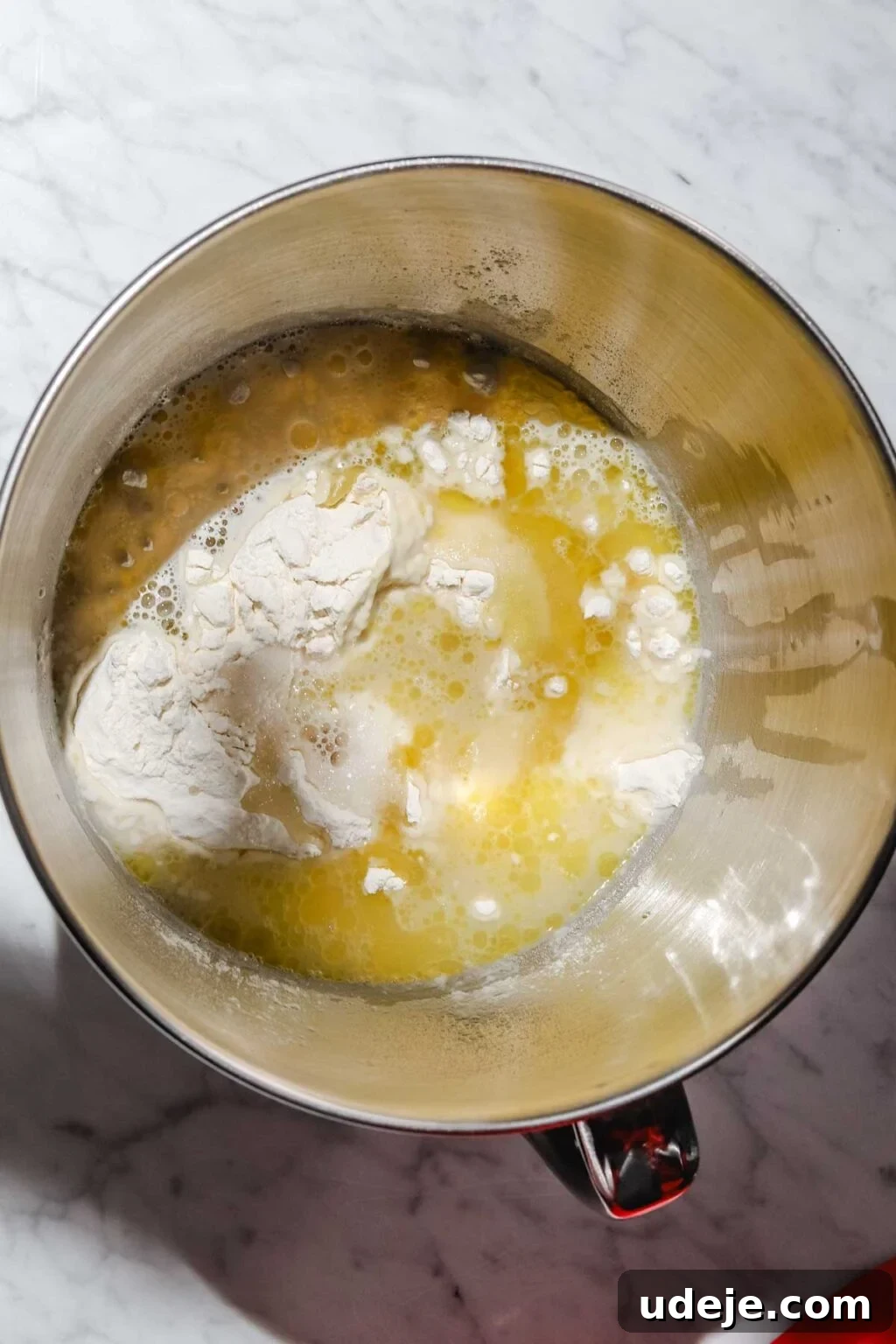 Mastering Homemade Shish Barak: Authentic Yogurt Dumplings 4 Shish Barak dough being prepared in a metal stand mixer bowl with water, olive oil, and flour on a light marble background.