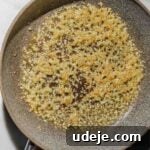 small saute pan with oil and minced garlic cooking on a light marble background