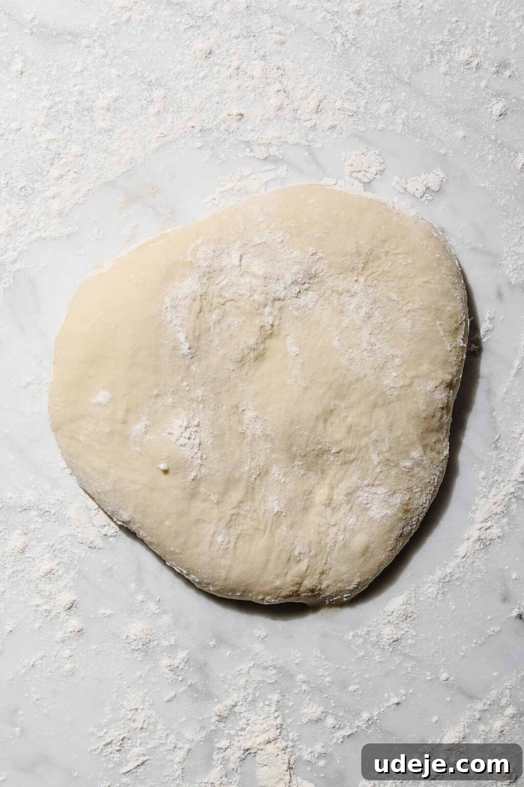 Mastering Homemade Shish Barak: Authentic Yogurt Dumplings 9 Shish Barak dough balls resting on a lightly floured light marble background, ready for rolling.