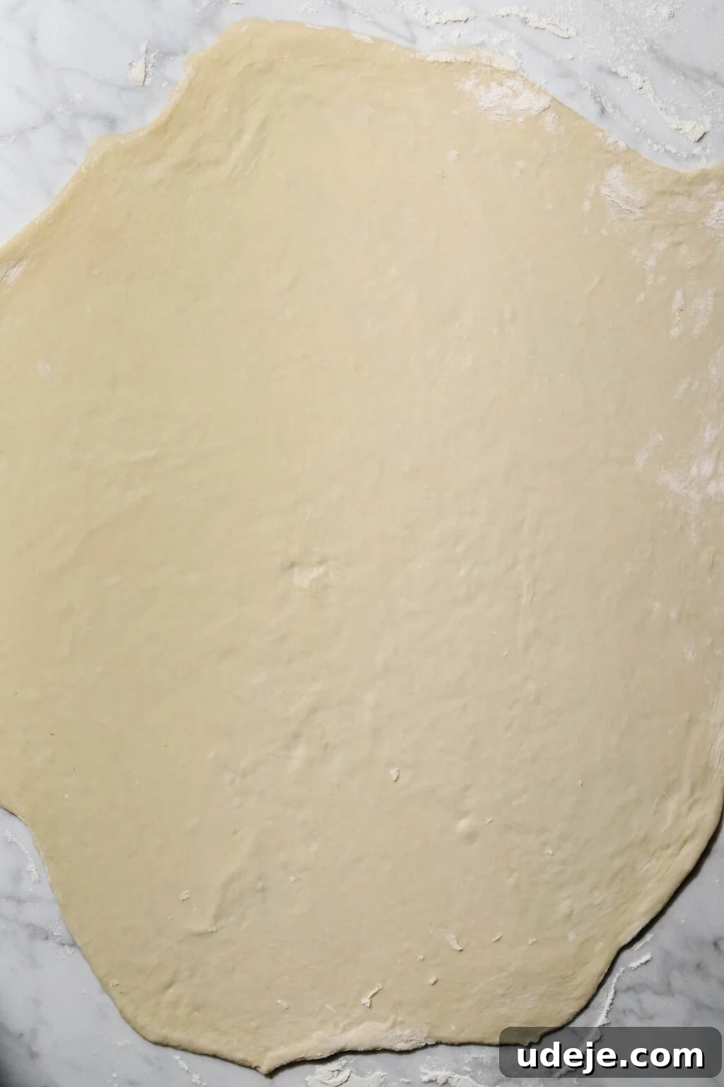 Mastering Homemade Shish Barak: Authentic Yogurt Dumplings 10 Shish Barak dough rolled out into a large, thin circle on a floured marble background, showing its delicate consistency.