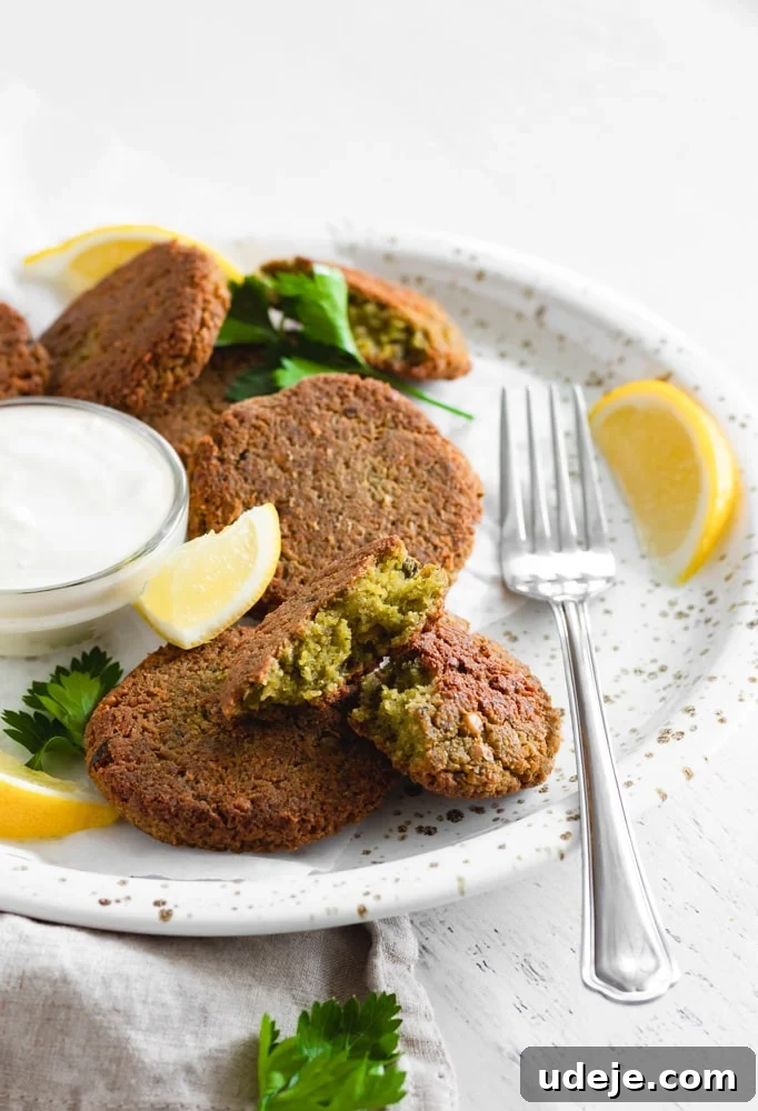 Perfectly Crispy Oven-Baked Falafel 3 A close-up of baked falafel patties arranged beautifully on a plate, adorned with fresh lemon wedges and scattered cilantro, highlighting their golden, crispy texture.