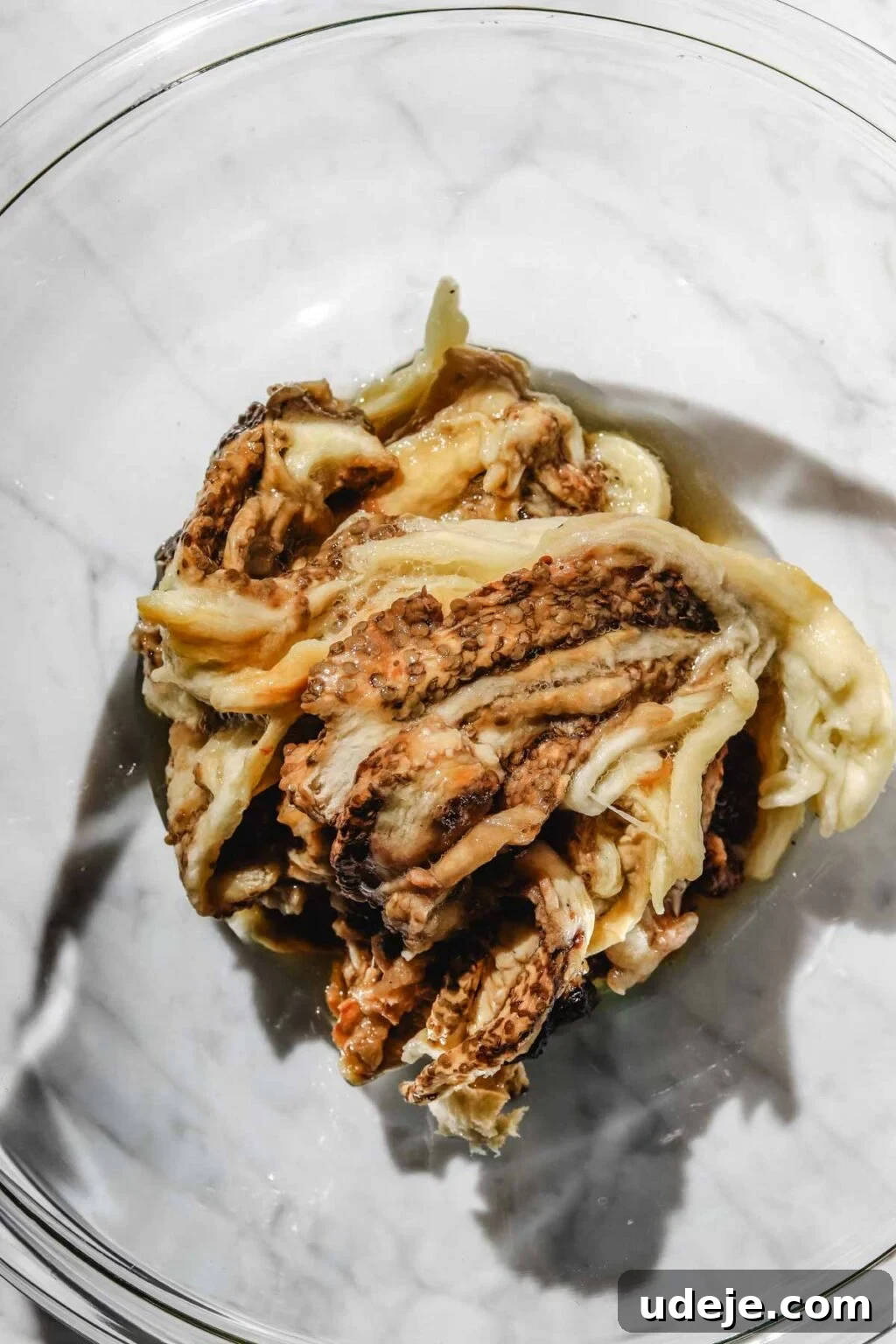 Smoky Mutabal: A Creamy Tahini Treat 9 Roasted eggplant flesh in a large glass bowl on a light marble background