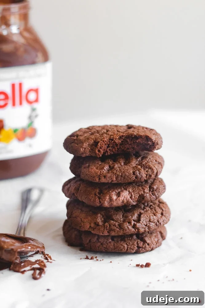 Nutella Cookie Bliss in 15 Minutes 5 Nutella cookies stacked on top of each other with a spoonful of Nutella to the left and a jar of Nutella to the back