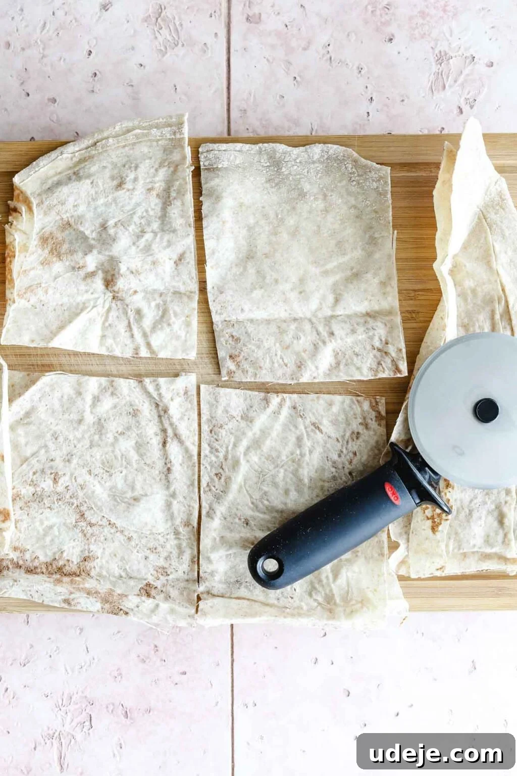Sumac-Spiced Chicken Musakhan Crisps 14 Markouk bread cut into rectangles with a pizza cutter on a light coloured wooden cutting board on a light coloured tile backdrop, ready for filling.