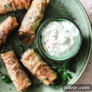 Musakhan rolls in a green plate with a yogurt dip in a small bowl on a light coloured tile background
