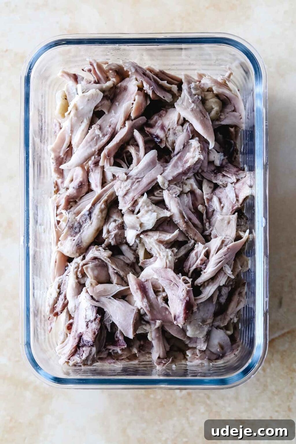 Sumac-Spiced Chicken Musakhan Crisps 9 Shredded chicken in a glass container on a light coloured background, ready for the Musakhan filling.