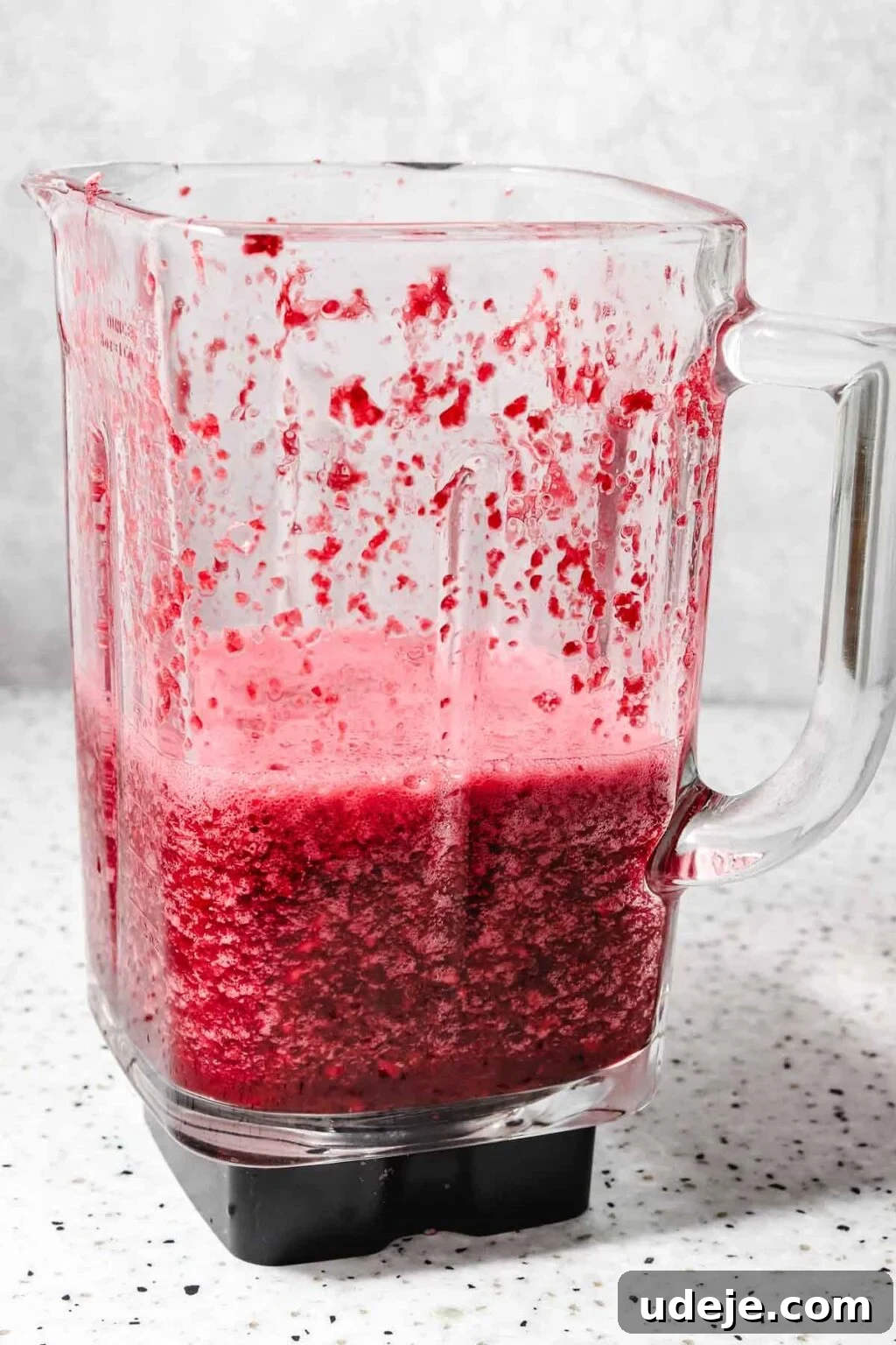 Homemade Pomegranate Molasses: Sweet, Tangy, and Versatile 18 blended pomegranate seeds in a glass blender on a speckled background