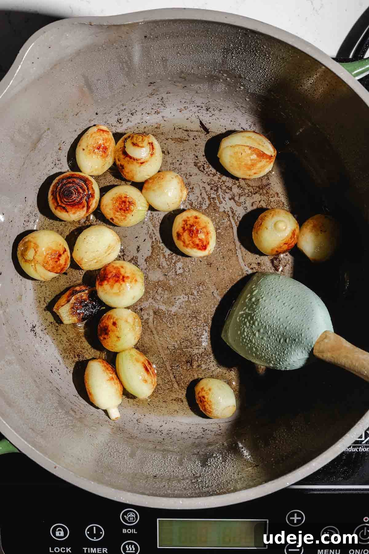 Lebanese Moghrabieh Pearl Couscous Delight 11 caramelized pearl onions in a large pot with a spatula inside, over an induction element