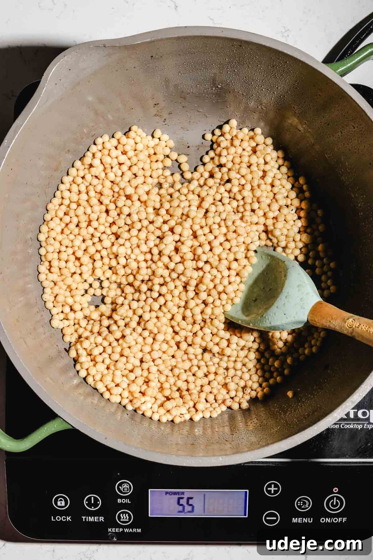 Lebanese Moghrabieh Pearl Couscous Delight 12 moghrabieh pearl couscous uncooked in a large pot with a spatula inside, over an induction plate