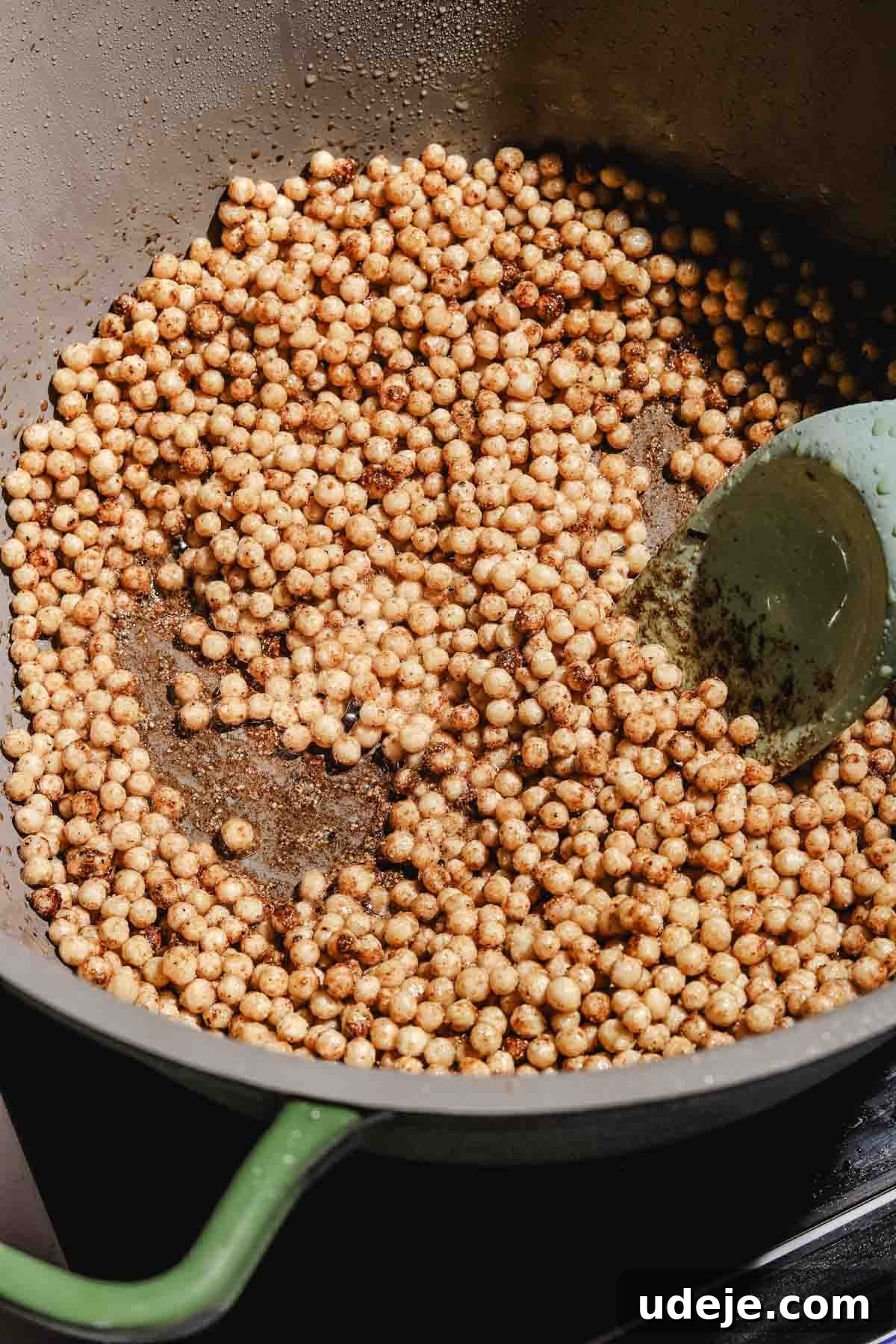 Lebanese Moghrabieh Pearl Couscous Delight 13 moghrabieh pearl couscous with spices being cooked in a pot, with a spatula inside