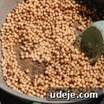 moghrabieh pearl couscous with spices being cooked in a pot, with a spatula inside
