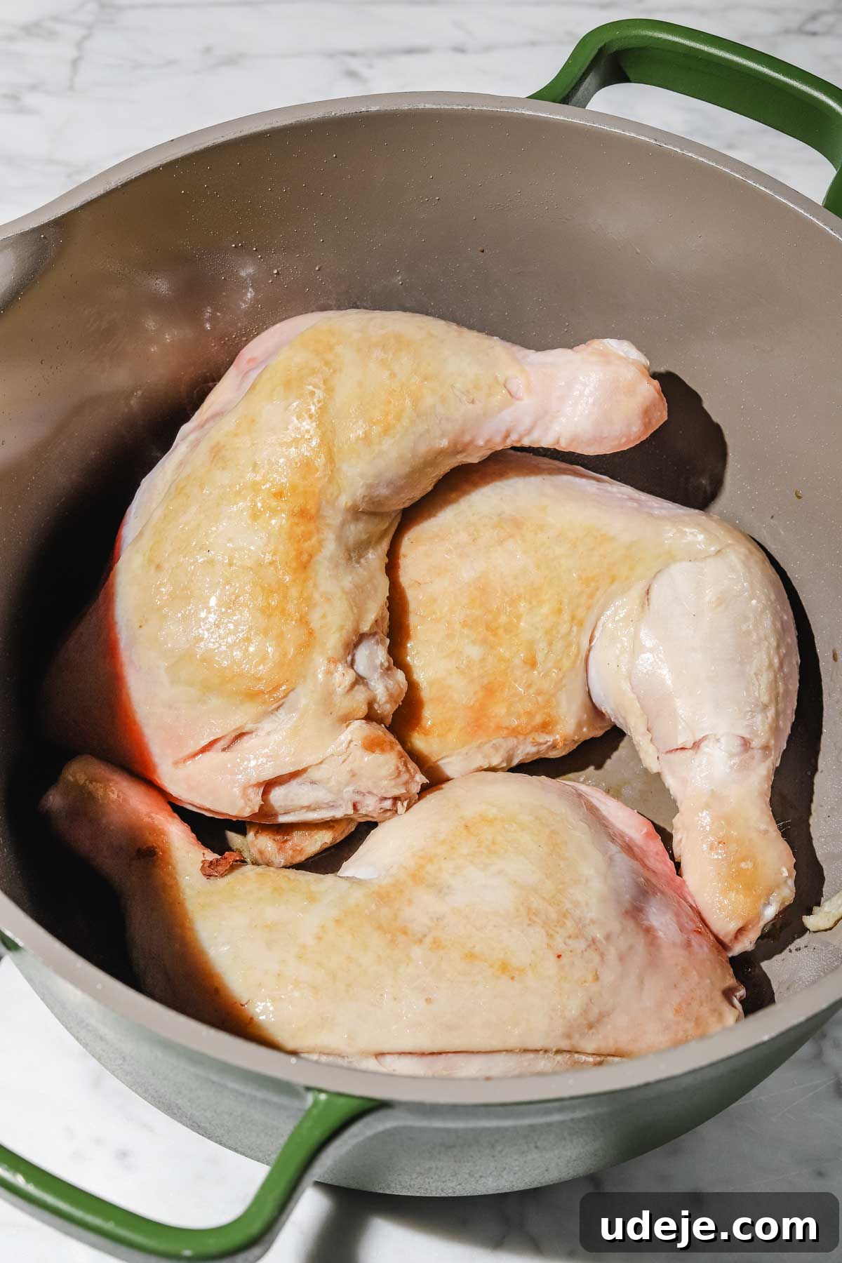 Lebanese Moghrabieh Pearl Couscous Delight 6 Chicken leg quarters browned in a large grey and green stock pot on a marbled background
