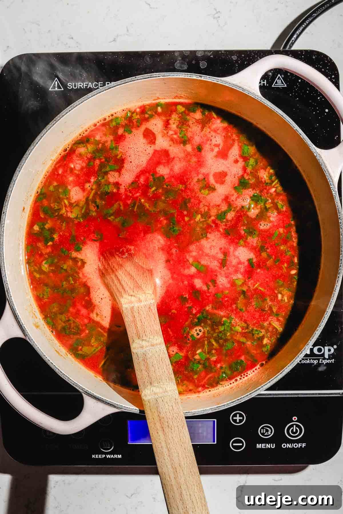 Moroccan Loubia A Flavorful Vegetarian White Bean Stew 9 Moroccan loubia in a large beige pot with a wooden spoon on black hotplate on a marble background