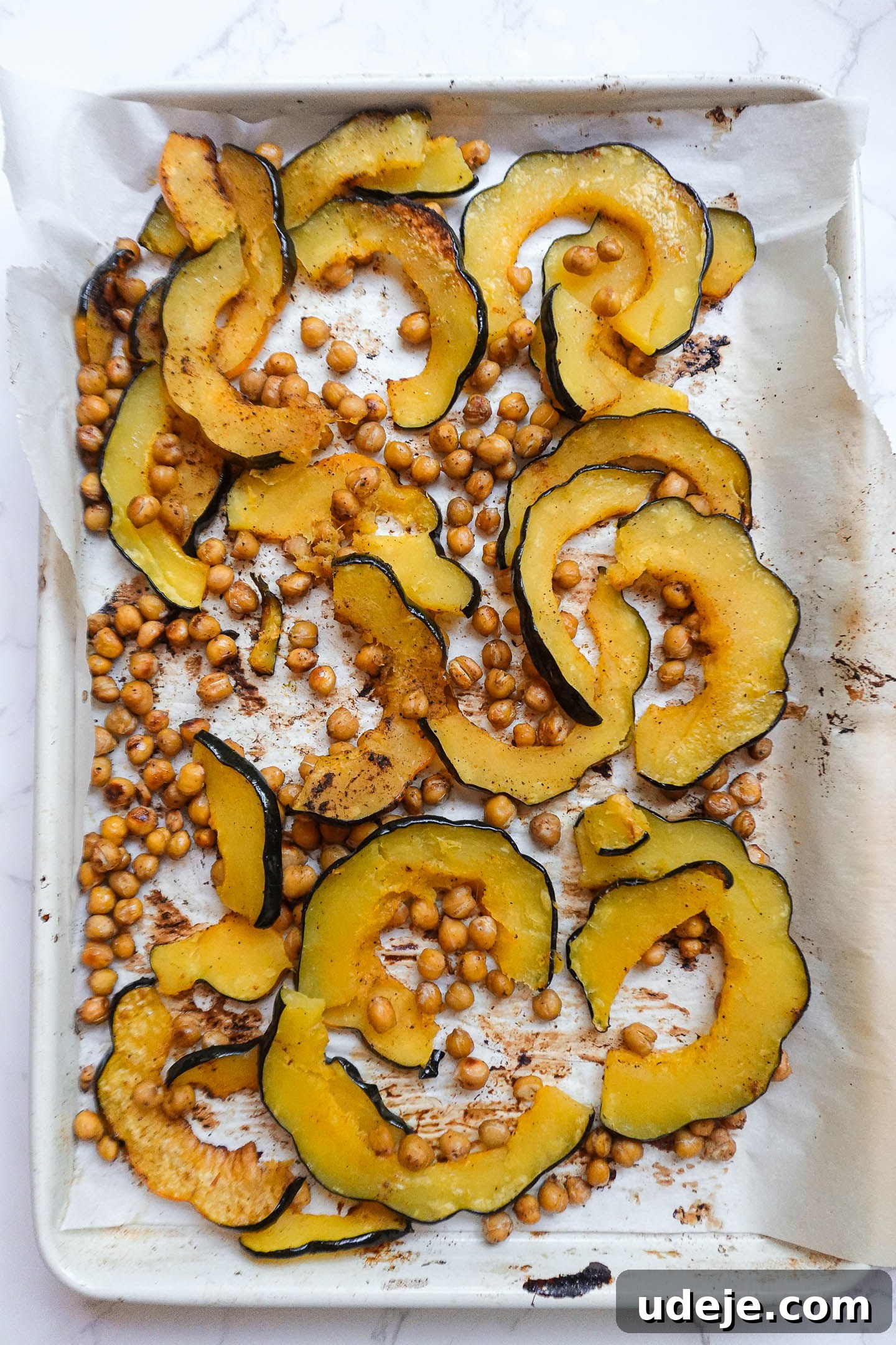 Roasted Acorn & Kale Salad with Maple Tahini 4 Golden-brown roasted acorn squash and crispy chickpeas on a baking sheet after baking.