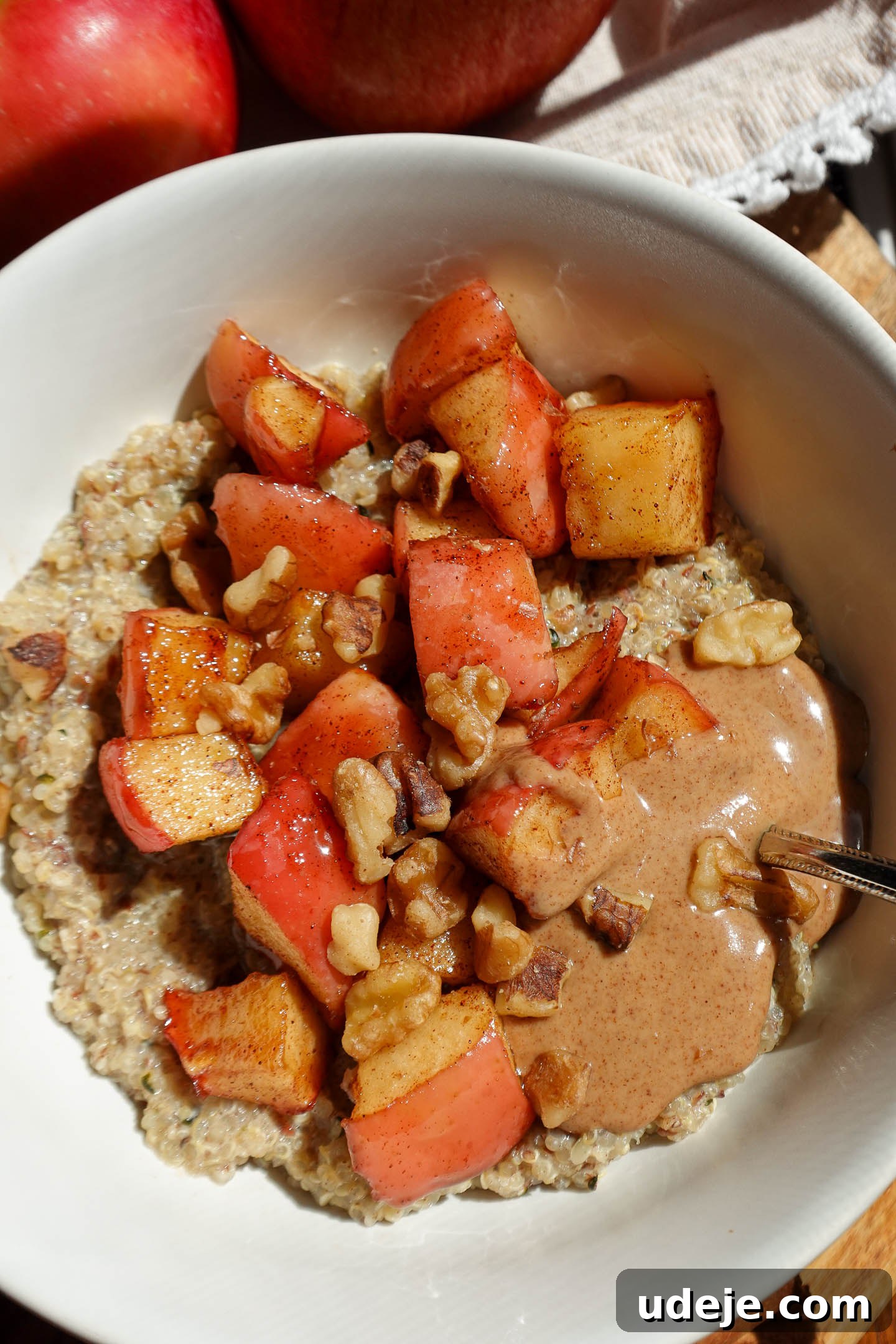 Cozy Vegan Apple Cinnamon Quinoa Breakfast Bowl 3 close up shot of Vegan Cinnamon Apple Quinoa Porridge in a bowl with a spoon of almond butter
