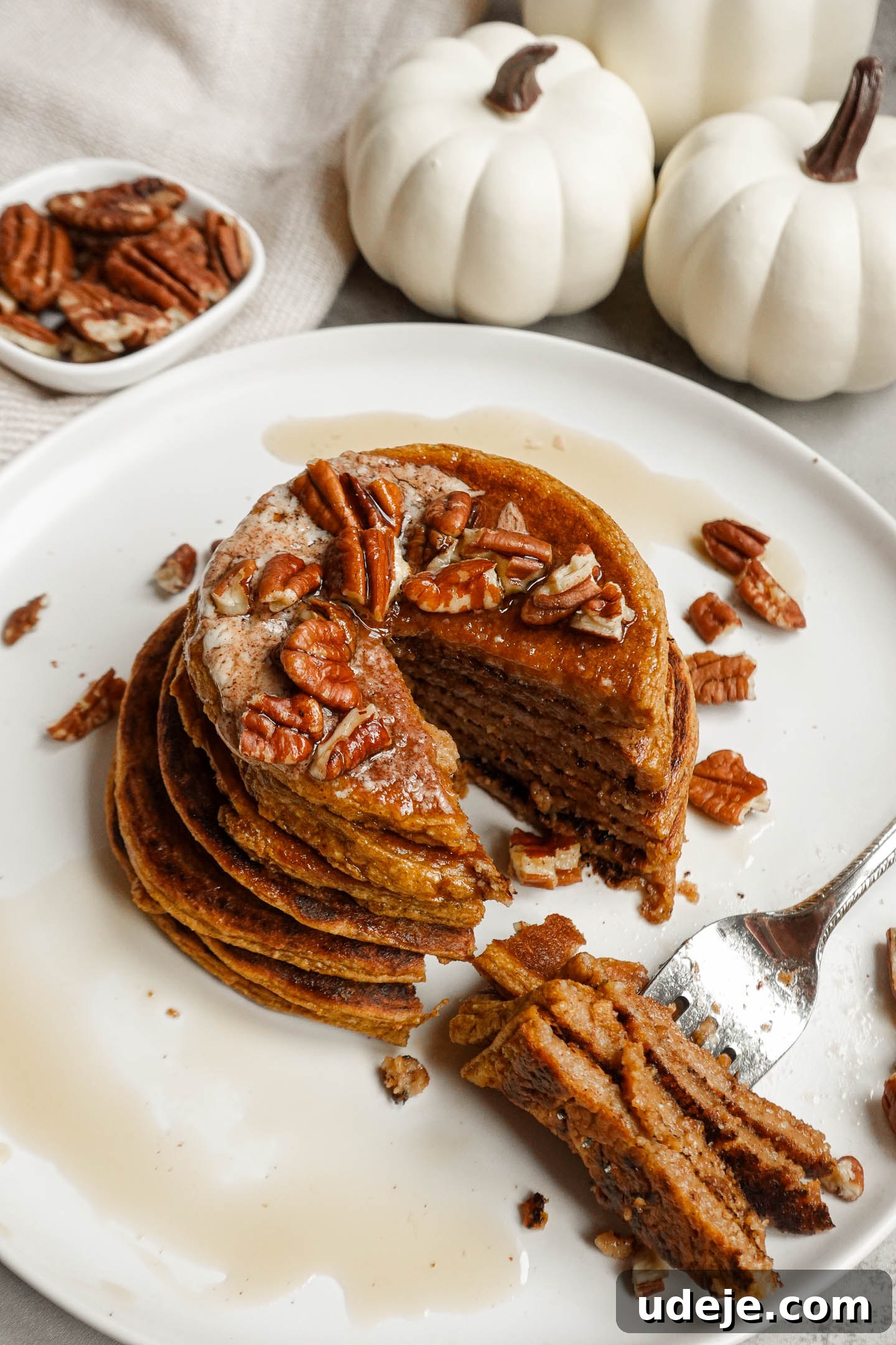Cozy Vegan Pumpkin Pancakes with Spiced Cinnamon Butter 4 A beautifully presented stack of fluffy gluten-free pumpkin pancakes, topped with a generous dollop of homemade dairy-free cinnamon butter, crunchy chopped pecans, and a delicate drizzle of maple syrup, capturing the essence of a perfect autumn breakfast.