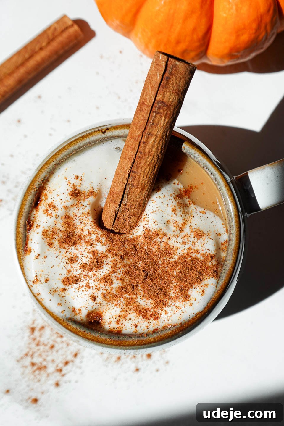 Warming Pumpkin Spice Chai Latte 3 Overhead shot of a pumpkin spice chai tea latte garnished with a cinnamon stick, presented on a beautifully themed fall table setting.