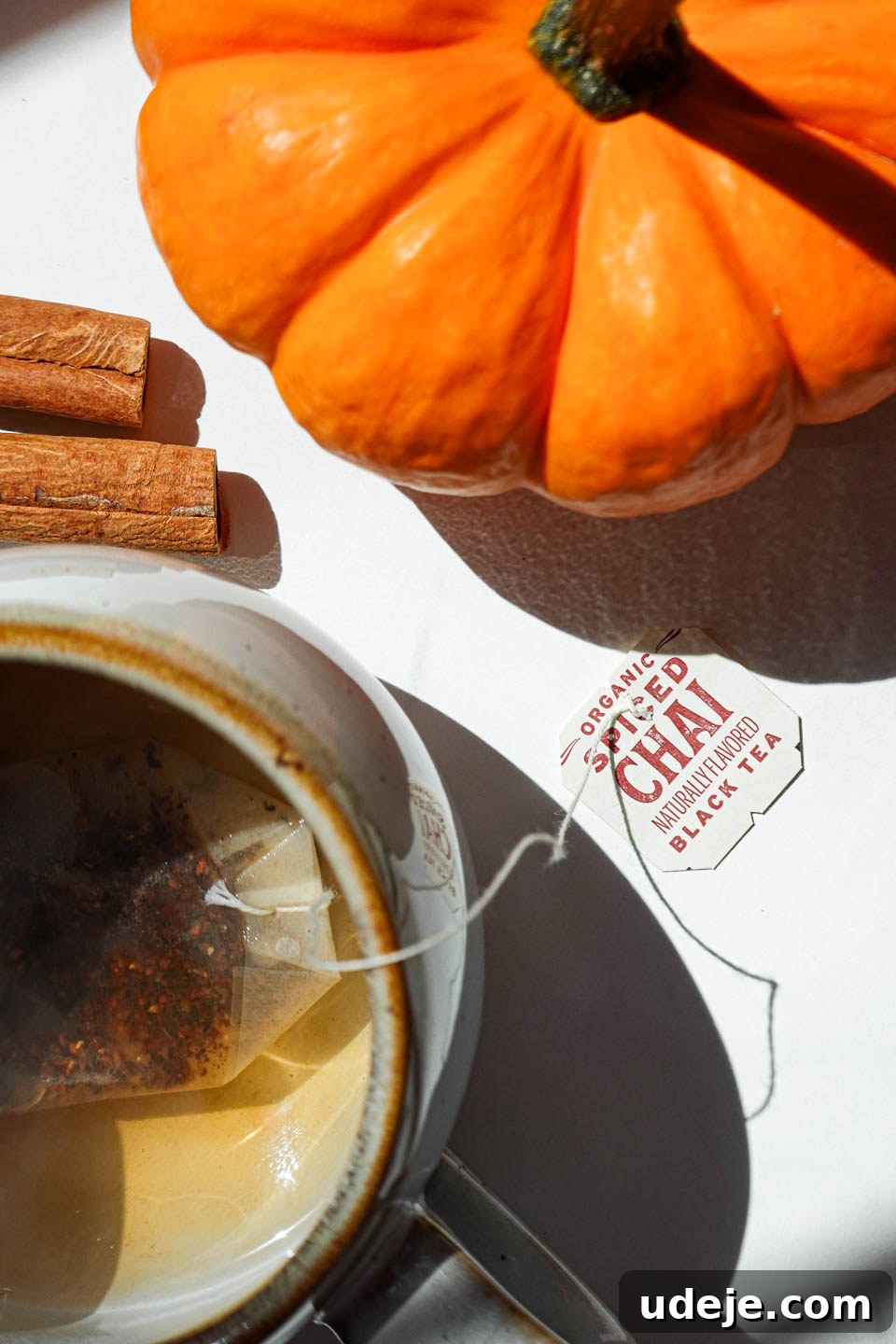 Warming Pumpkin Spice Chai Latte 5 A chai tea bag steeping in hot water within a white ceramic mug, steam gently rising.