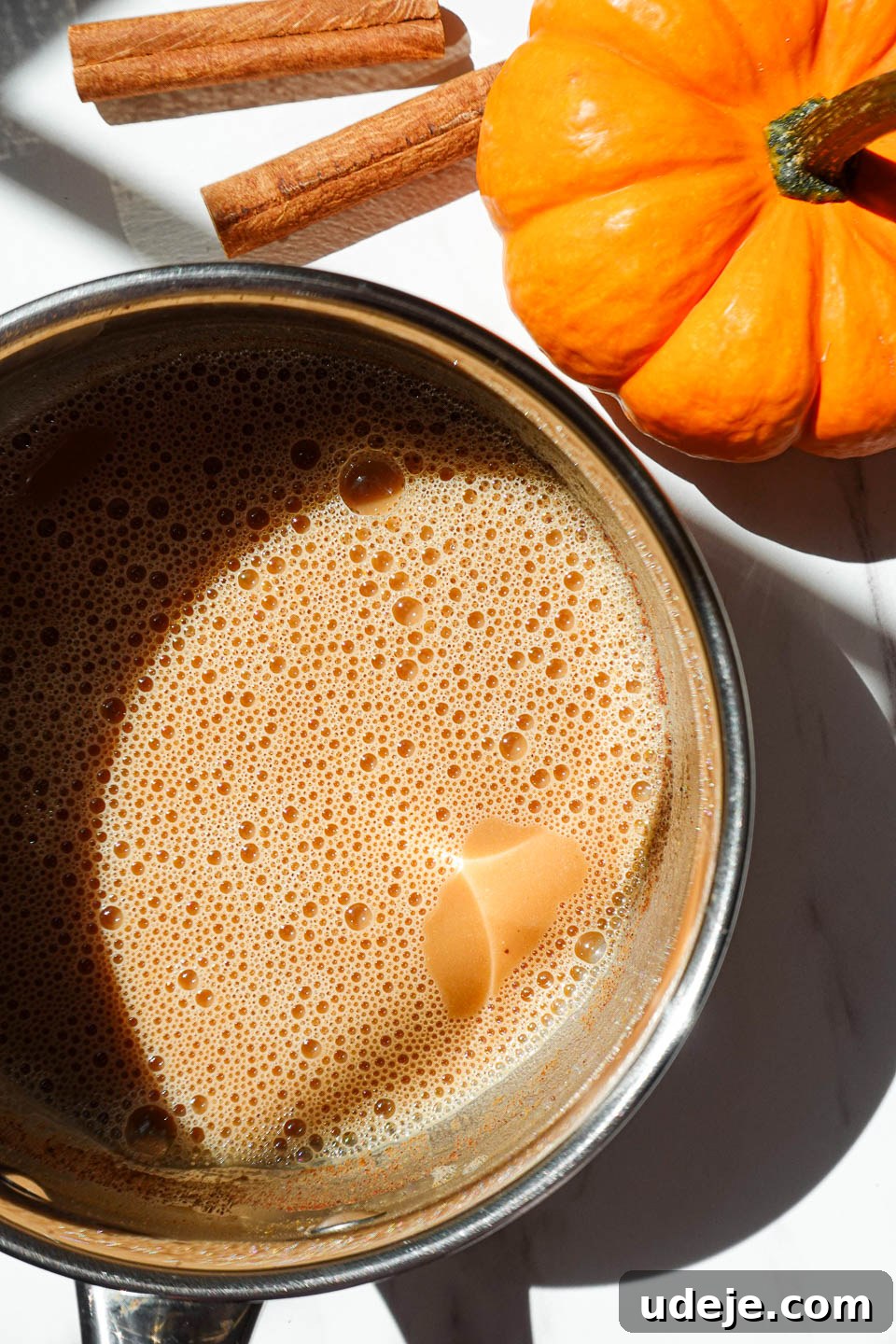 Warming Pumpkin Spice Chai Latte 6 A creamy pumpkin milk mixture gently steaming in a small saucepan, being whisked over low heat.