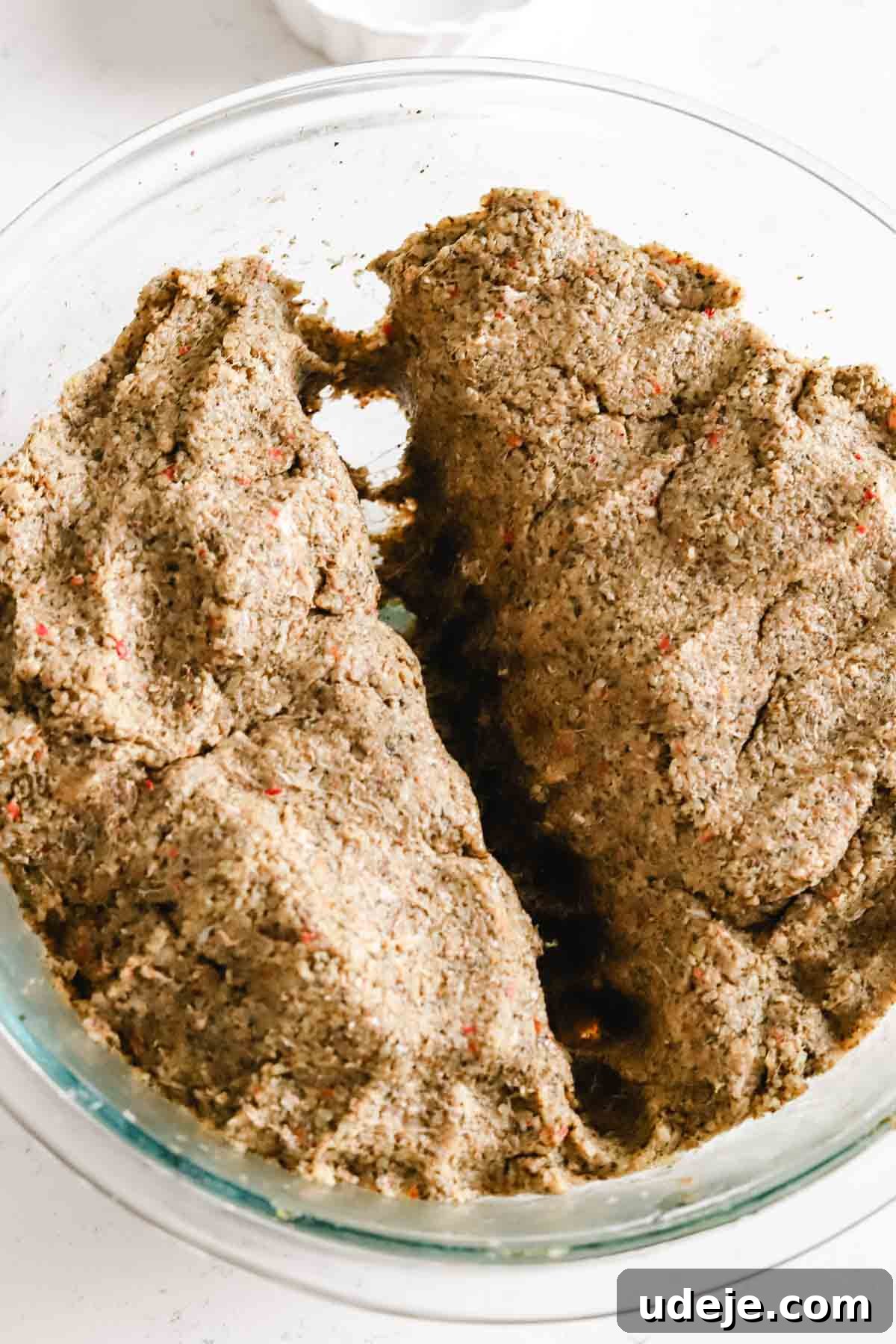 Baked Kibbeh Casserole 13 Kibbeh dough divided in half in a glass bowl on a light marble background, ready for layering.