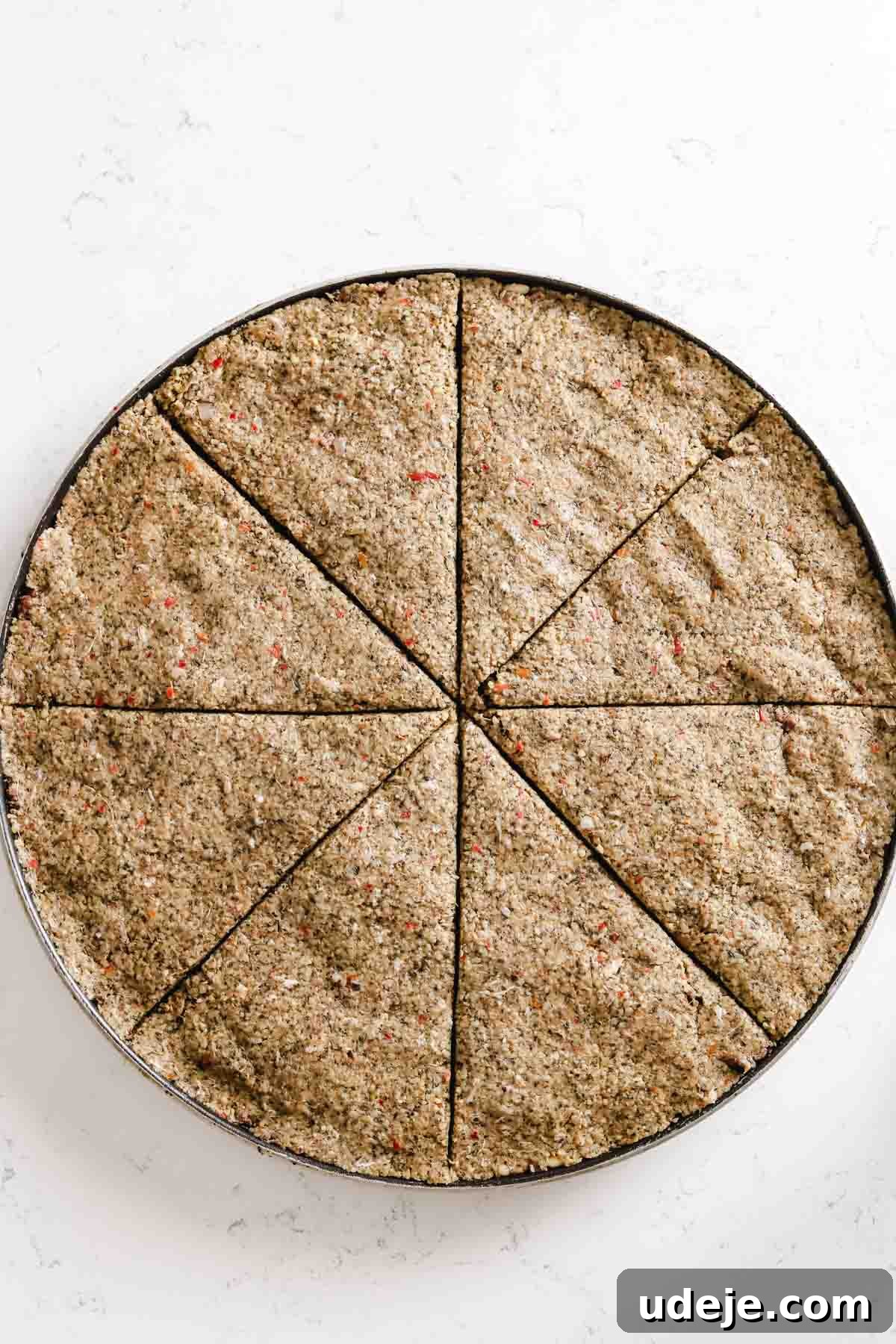 Baked Kibbeh Casserole 20 Unbaked Kibbeh bil Sanieh initially cut into eight triangular pieces in a large circular baking pan on a light marble surface, forming the base for the diamond pattern.