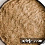 Fully spread out kibbeh dough on a circular baking pan on a light marble background