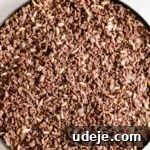 Sautéed ground beef and onions spread out on top of kibbeh dough on a round circular baking pan on a light marble surface