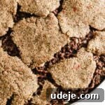 Kibbeh dough in circular pieces on top of sautéed ground beef in onions in a circular baking pan on a light marble background