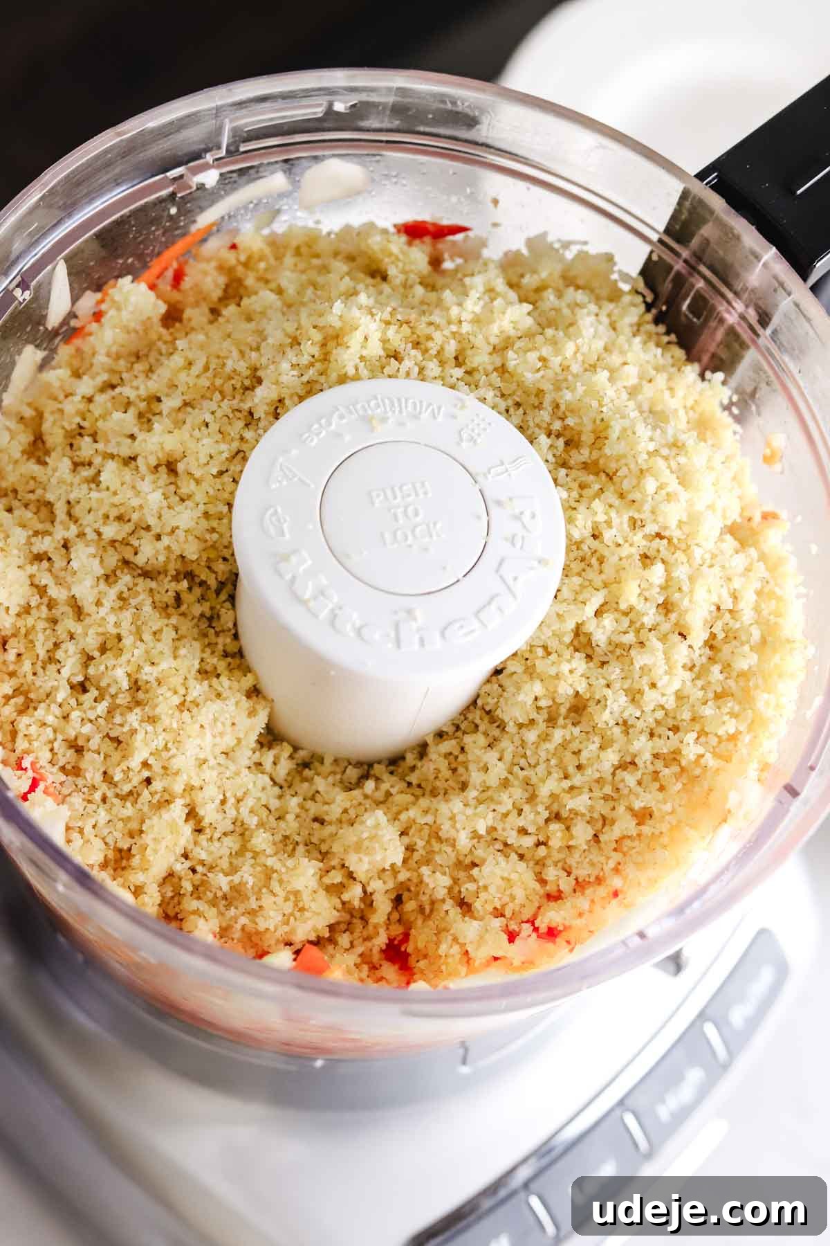 Baked Kibbeh Casserole 8 Finely chopped onions and red peppers with soaked fine bulgur added on top in a food processor, illustrating the next stage of dough preparation.