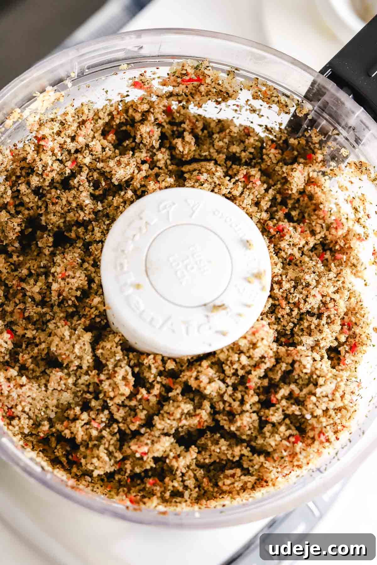 Baked Kibbeh Casserole 10 The processed mixture of fine bulgur, kamouneh spice, dried basil, dried mint, onions, and red peppers in a food processor, showing a smooth, blended texture before adding meat.